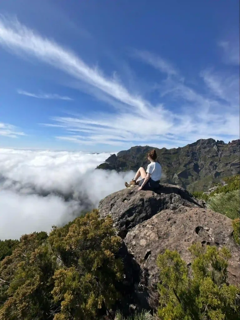 Laura sat on a rock in the sunshine above the clouds in Madeira
