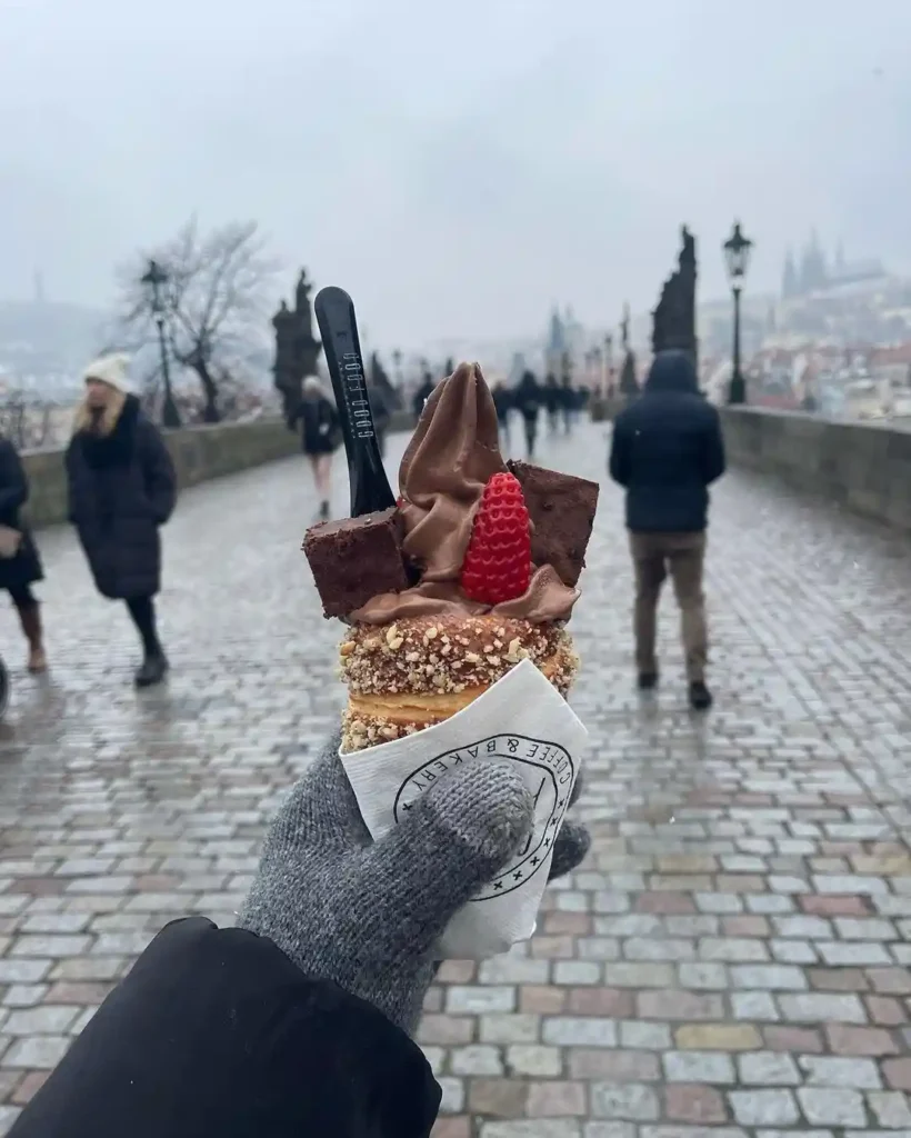 Laura holding out a trdelnik dessert in Prague