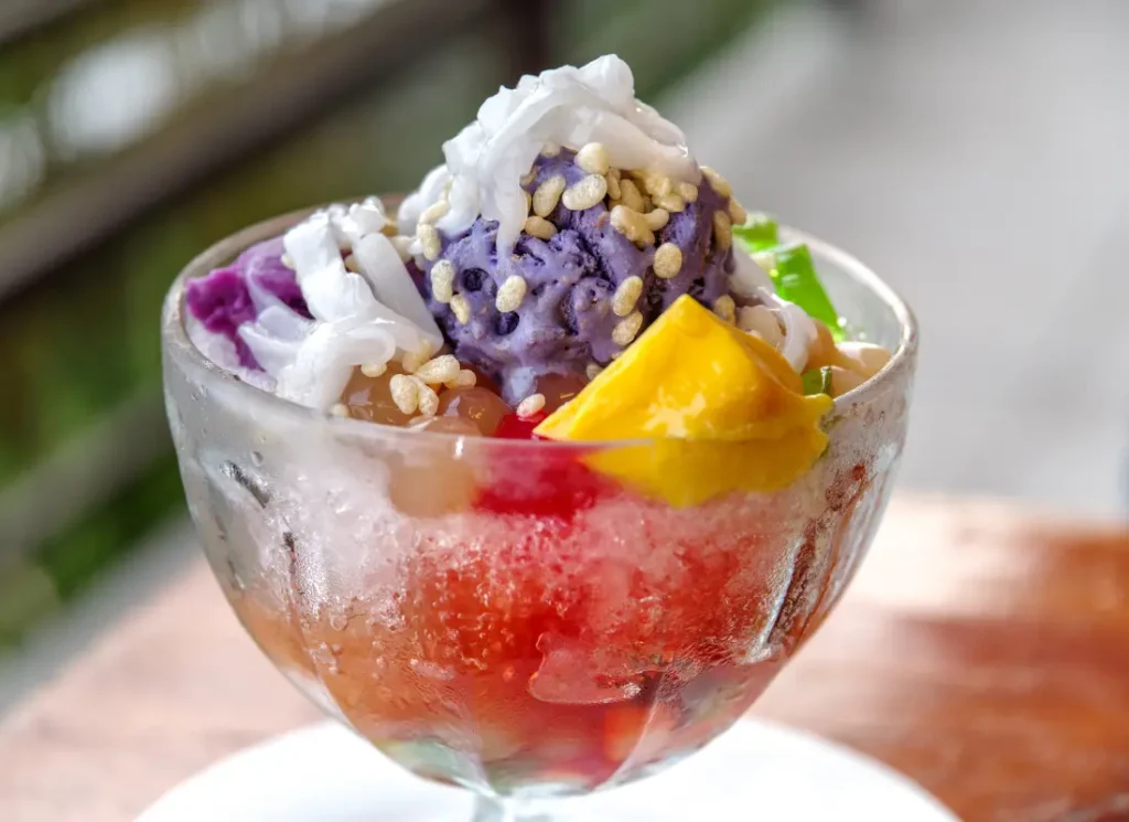 A bowl of filipino halo-halo topped with flan, jelly and ube ice cream