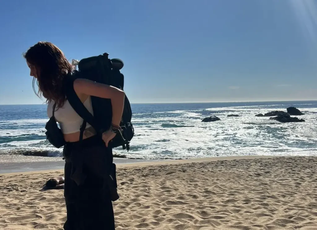 Isabella travelling on the beach in Chile with her backpack