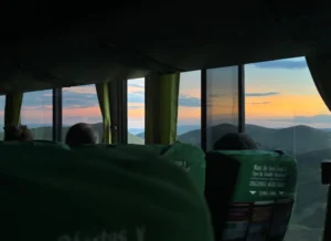 Three people looking out over the sunset on a Peru Hop bus