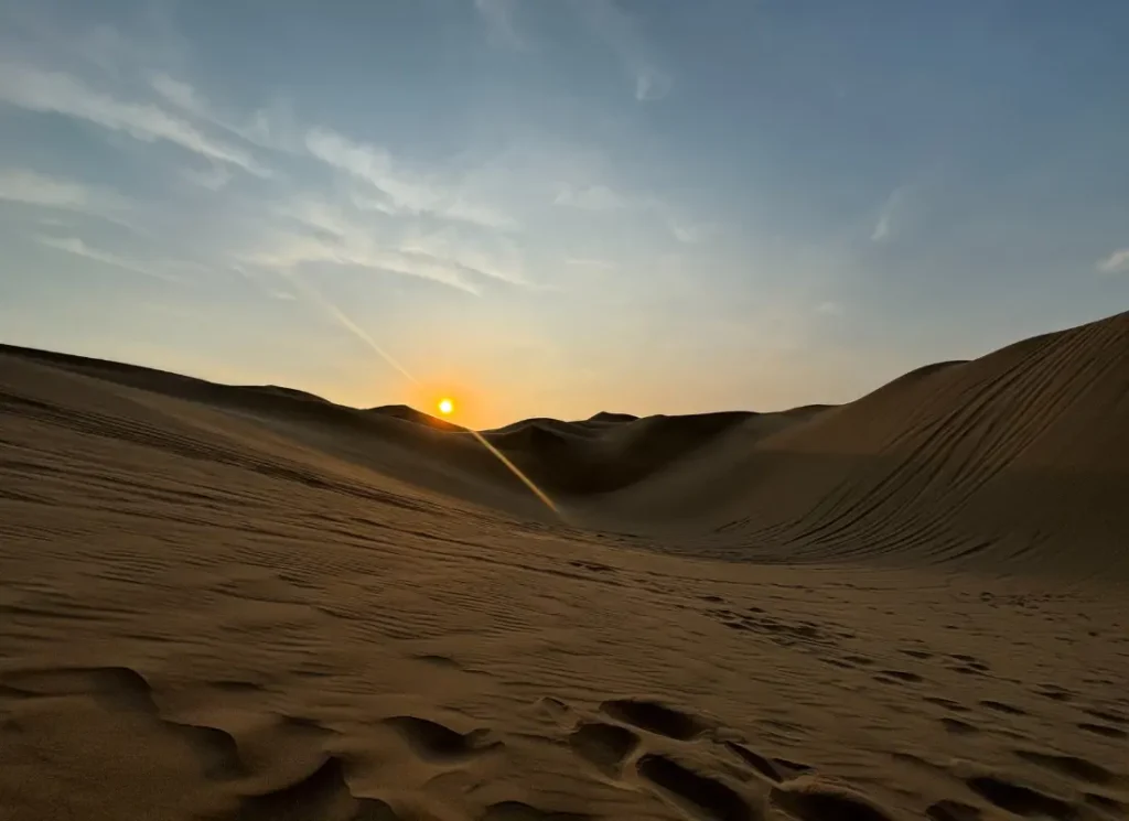 A sunset on the sand dunes after a sandboarding tour Huacachina Peru